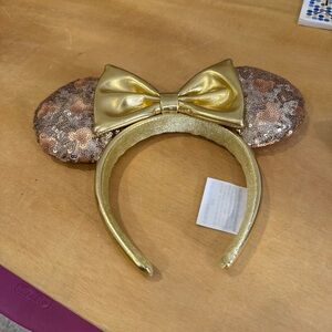 Disney Gold Sequin Minnie Mouse ear headband with a gold bow.